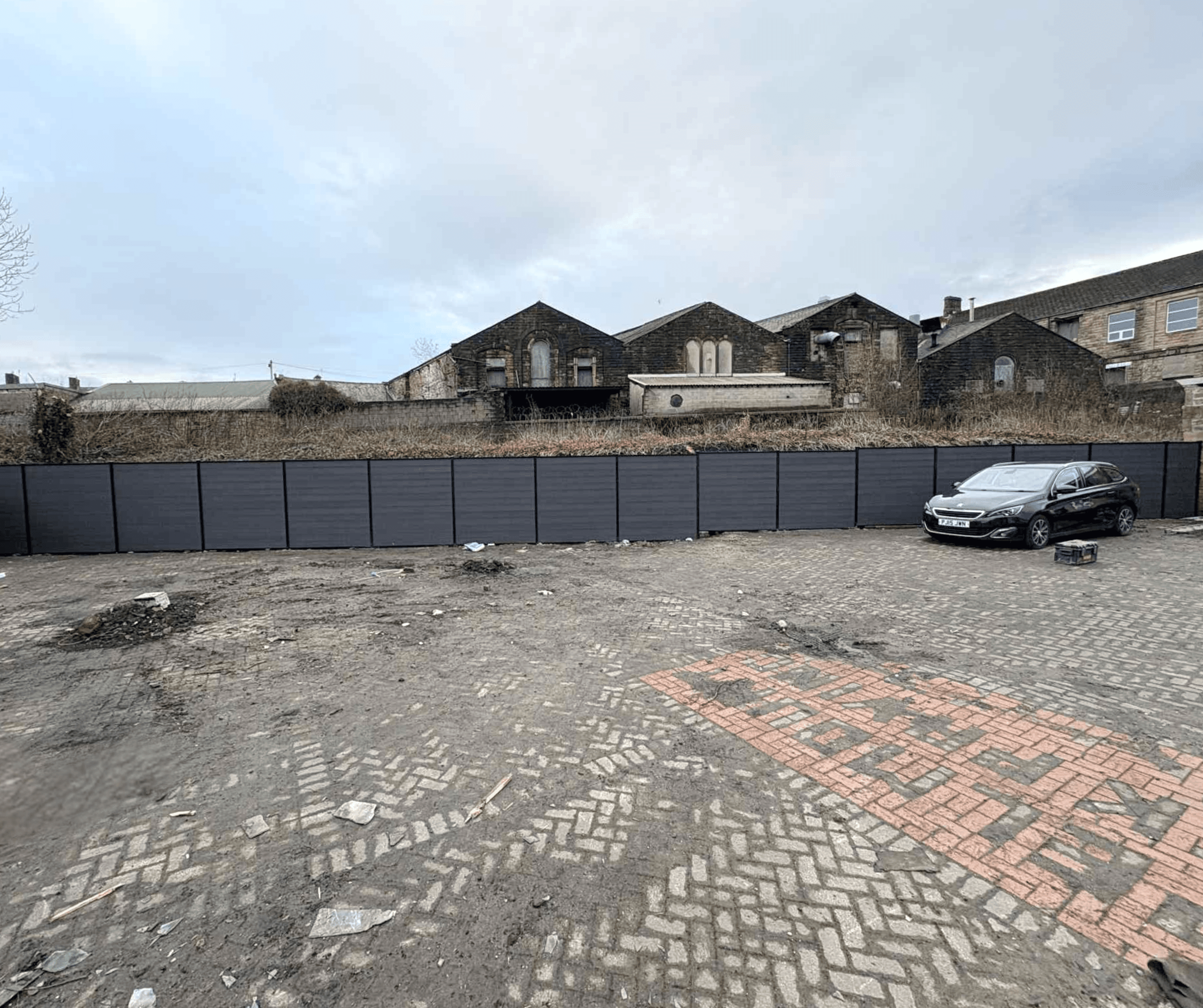 Block paved driveway area beside dark grey fencing