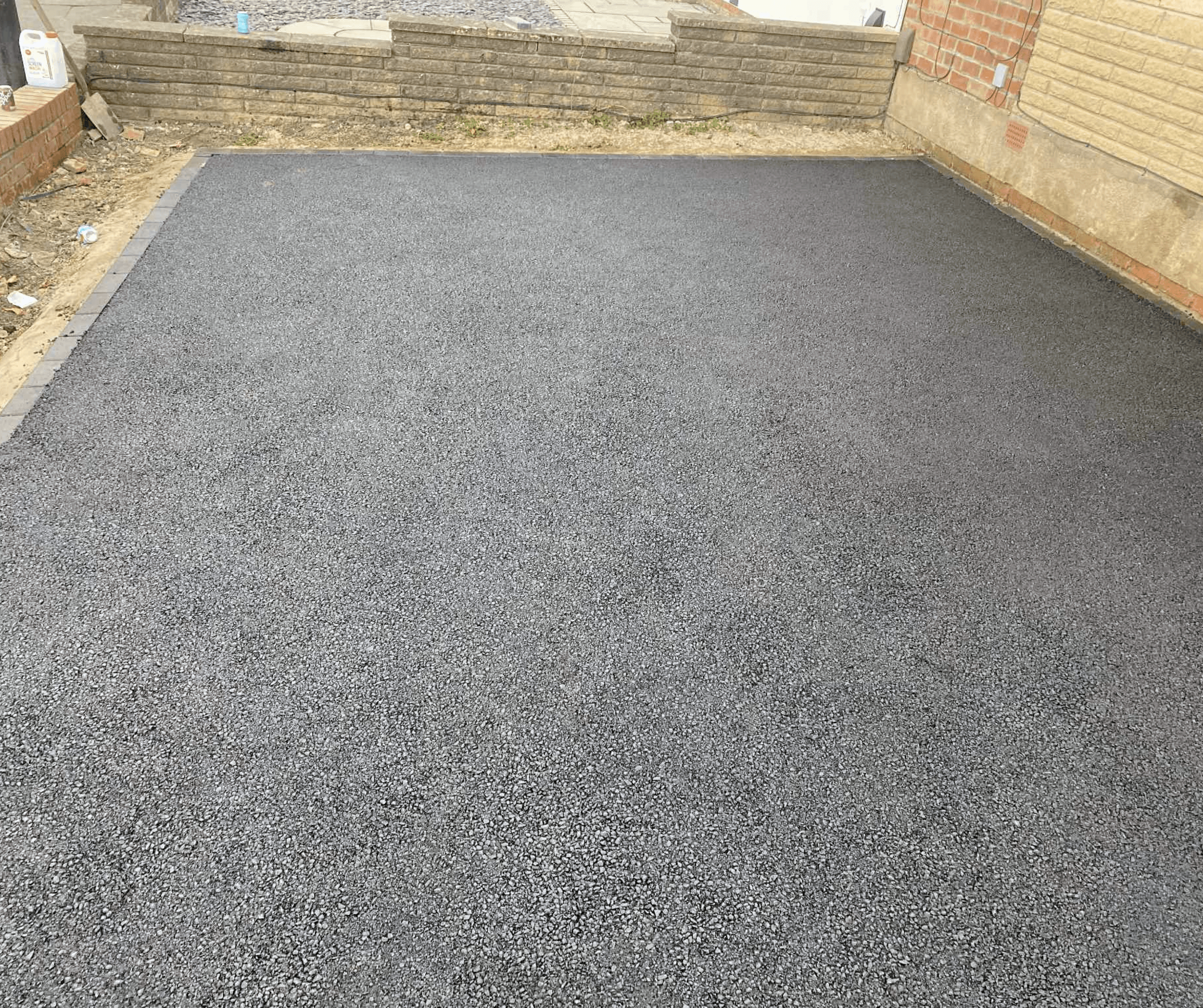 Freshly surfaced driveway enclosed by timber fencing