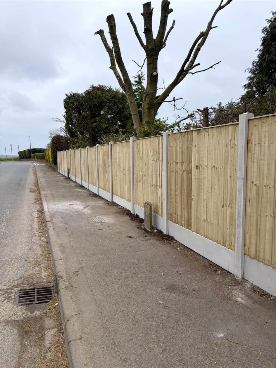 Closeboard timber fence on concrete posts along a lane