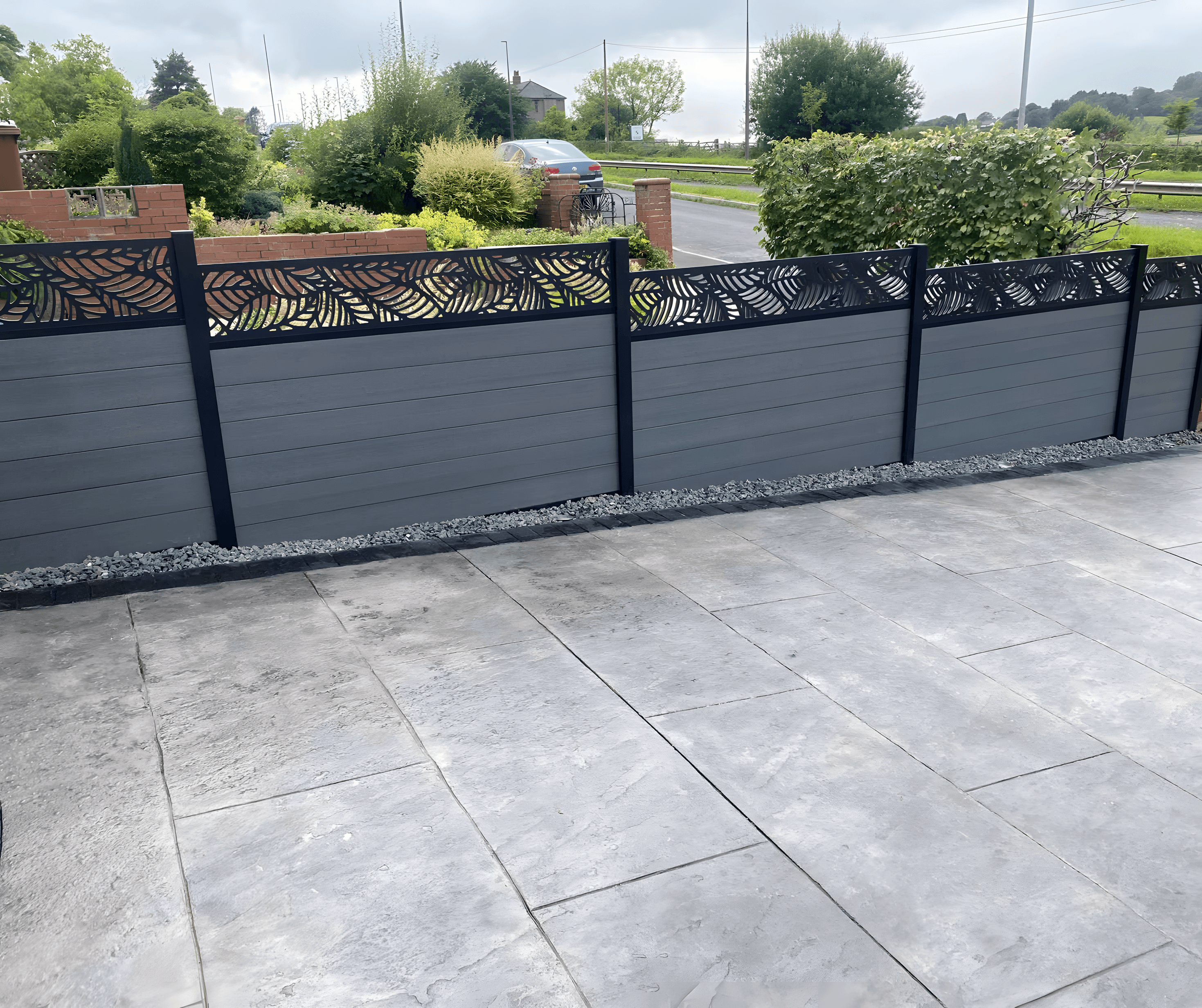 Grey composite fence with a decorative leaf-pattern top panel above a new patio