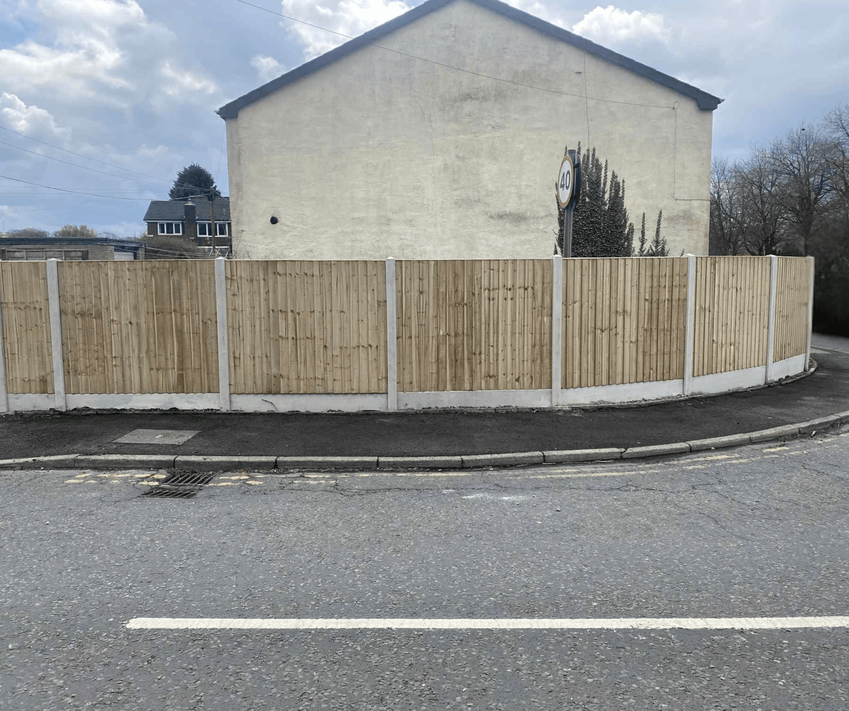 Timber fence panels on concrete posts and gravel boards beside a road