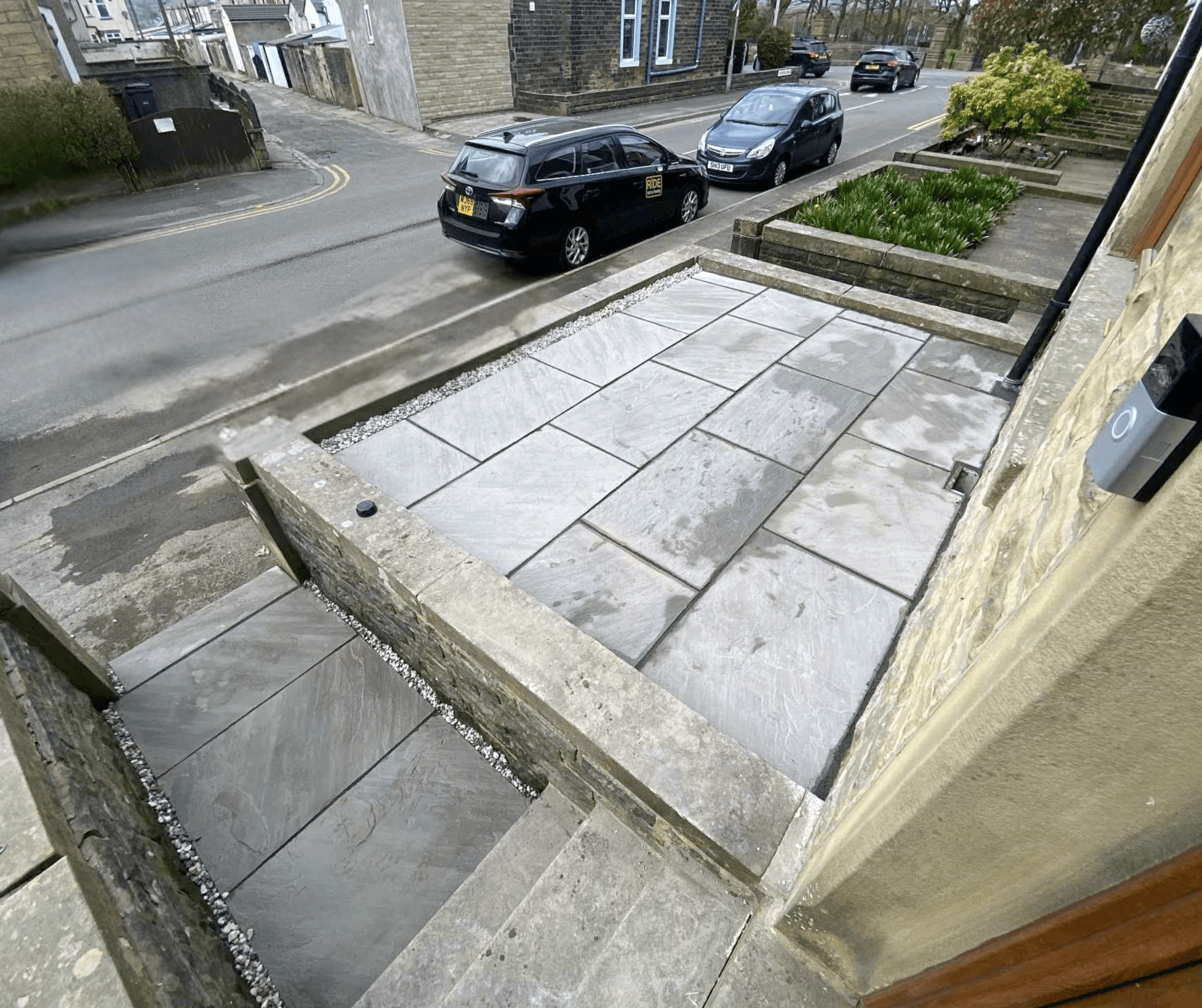 Front garden patio with grey slabs and a low wall by the street
