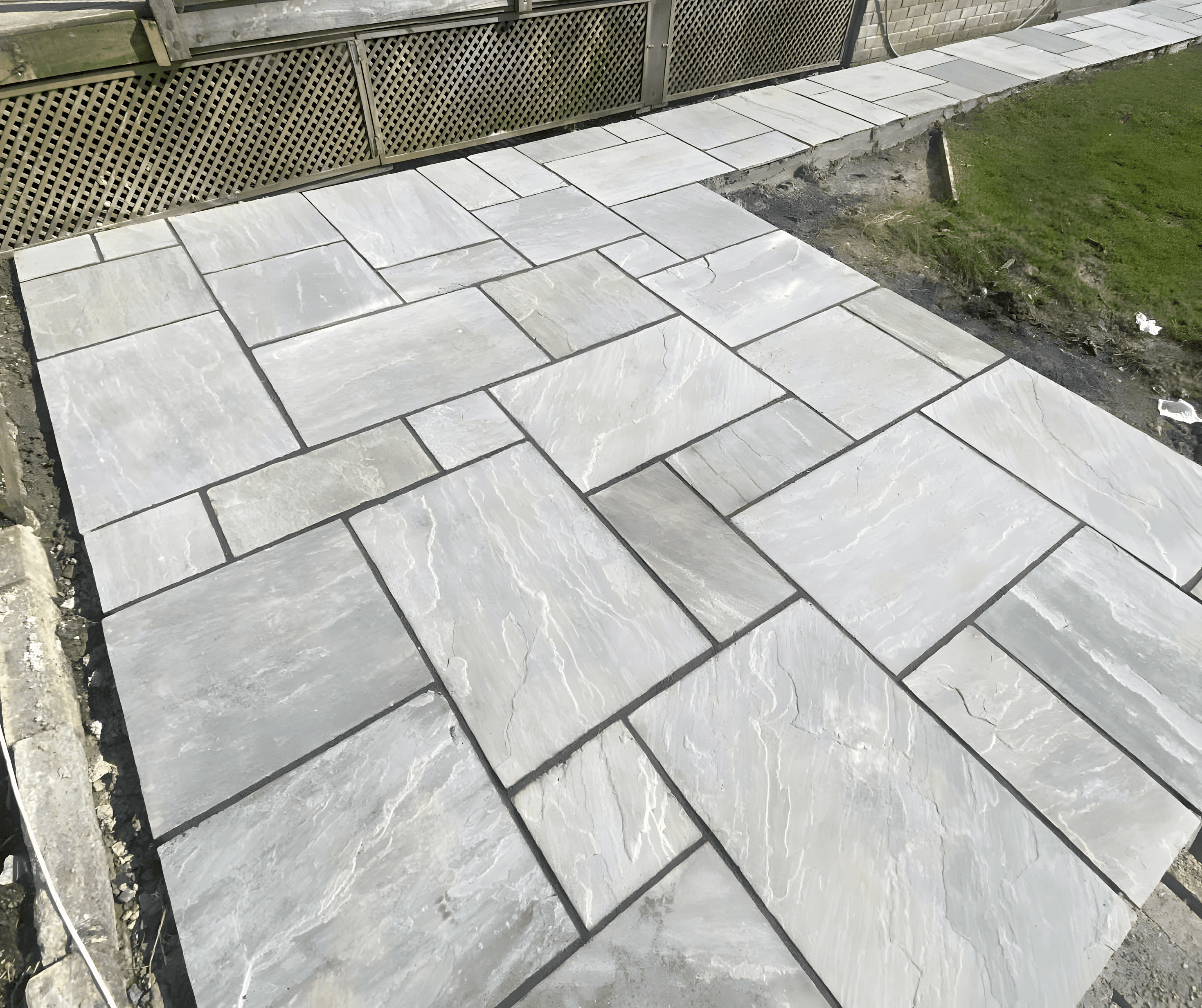 Newly laid grey patio slabs meeting a lawn edge