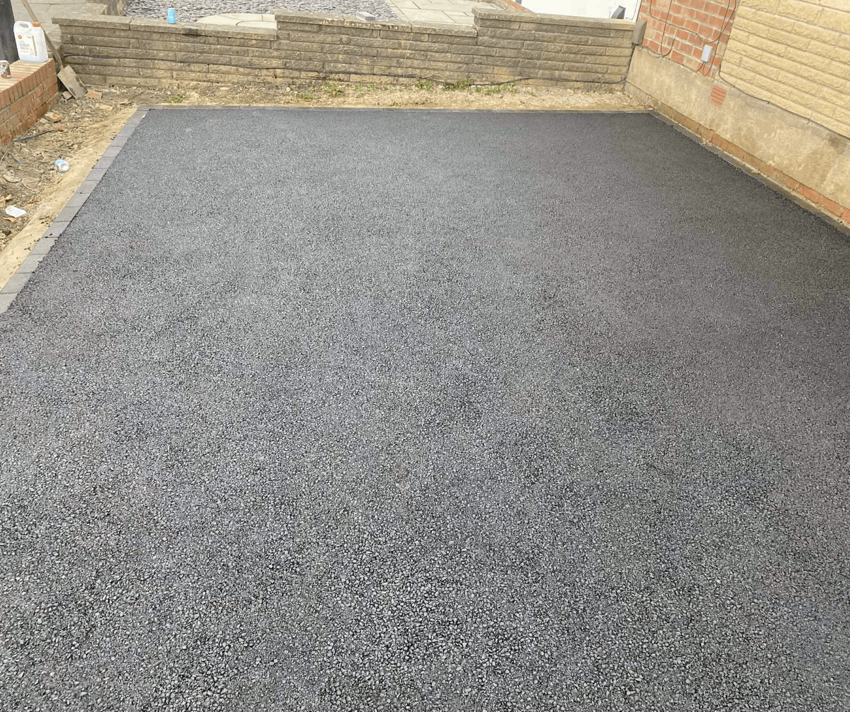 Freshly surfaced driveway enclosed by timber fencing