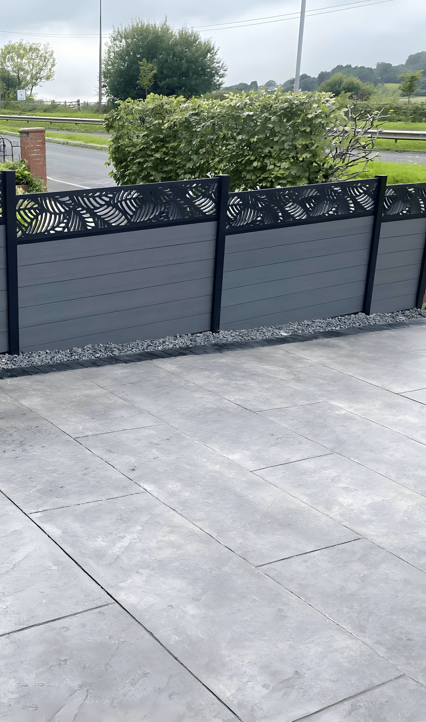Grey composite fence with a decorative leaf-pattern top panel above a new patio