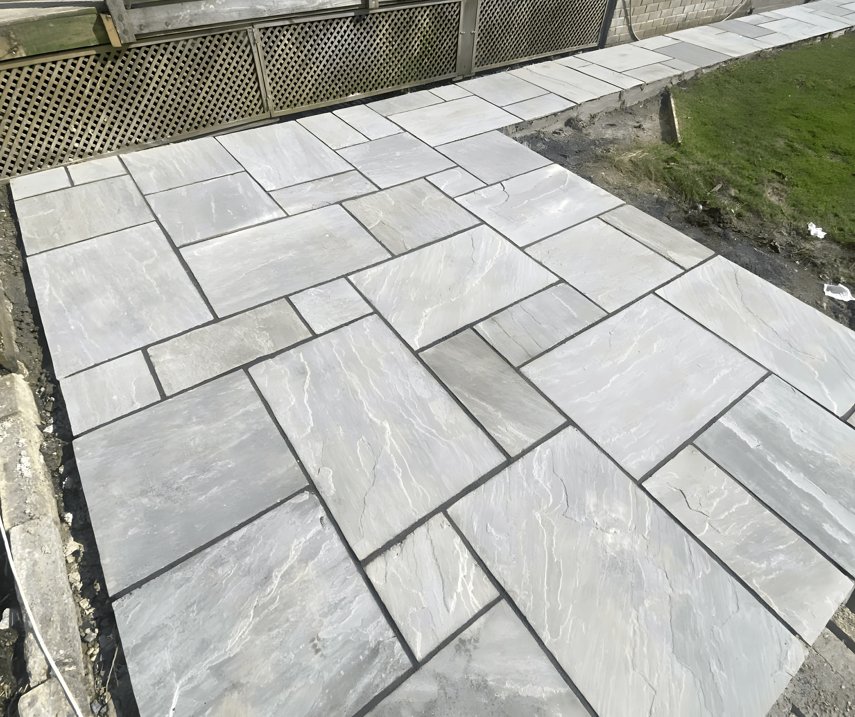 Newly laid grey patio slabs meeting a lawn edge